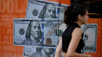 Una mujer camina junto a una imagen de billetes de cien dlares estadounidenses en Buenos Aires.